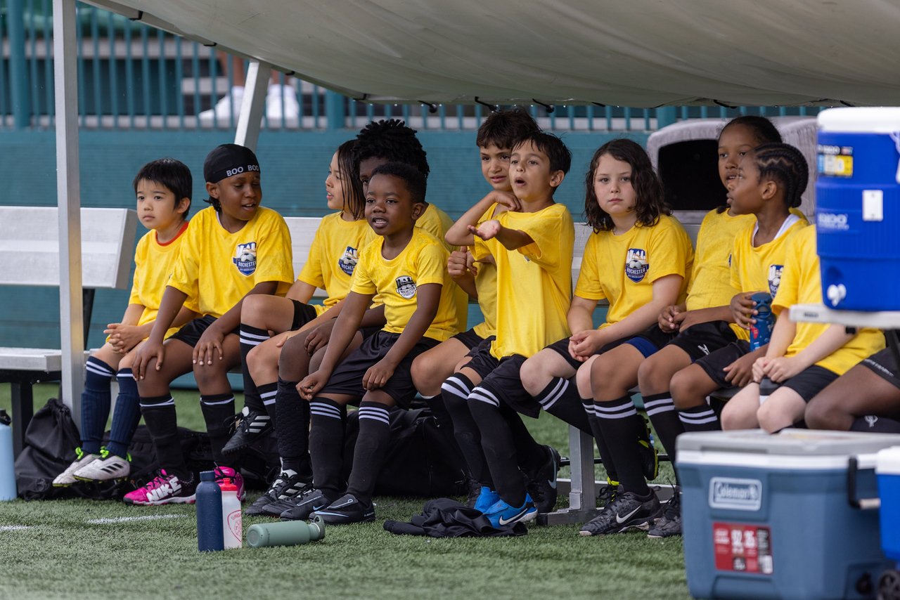 RCSL players in yellow jerseys sitting together on the team bench